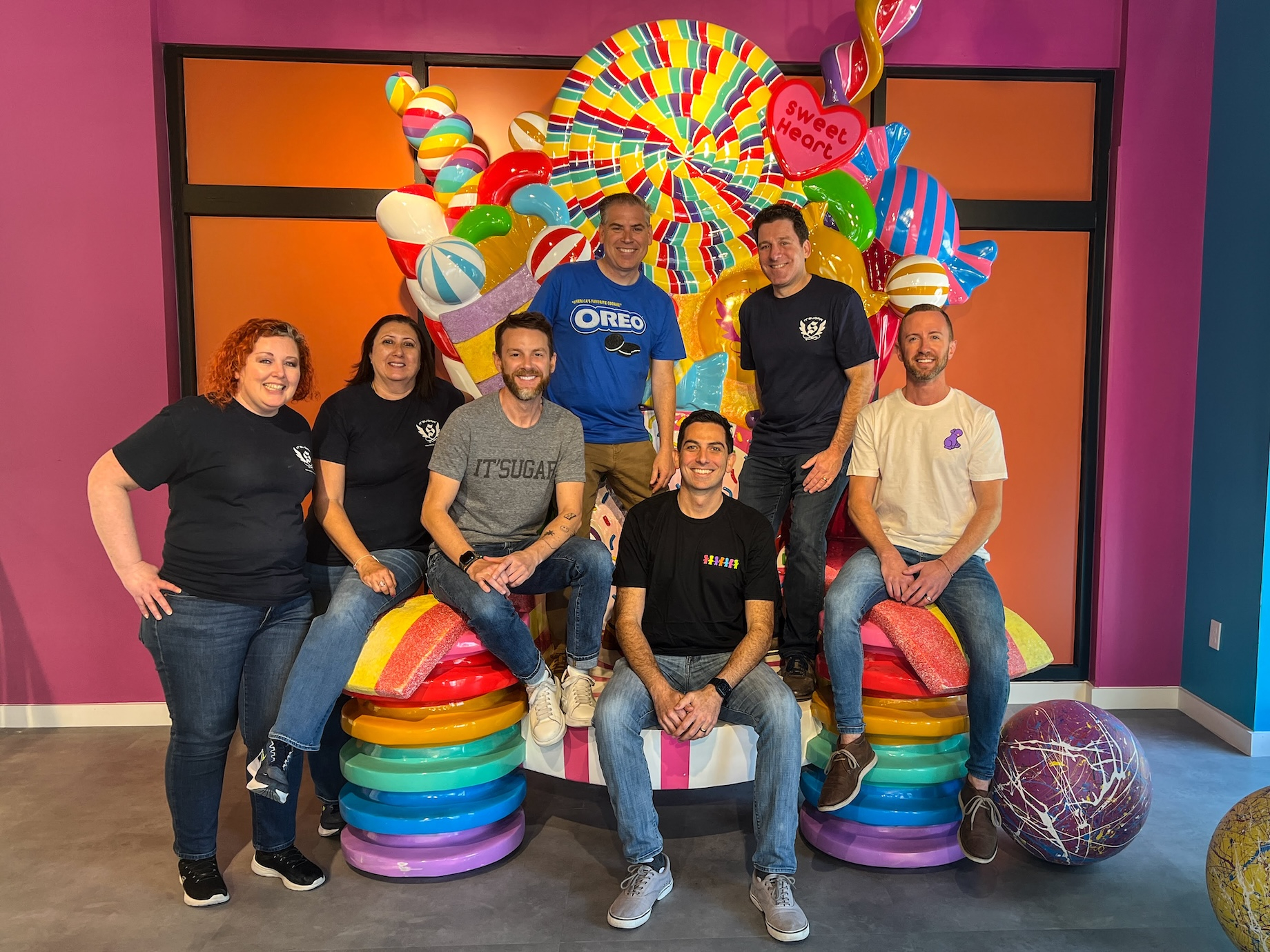 It’Sugar team members, including Jonathan Schwartz at front, sit on a candy throne during the April 2024 grand opening of its