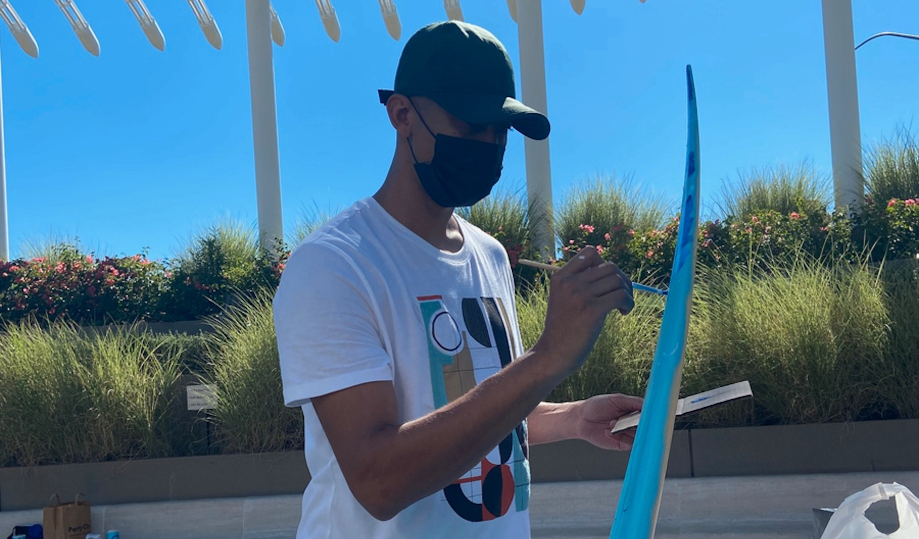 Sponsored by Village at La Floresta and by Regency Centers’ Southern California region, an artist adds color to surfboards pa